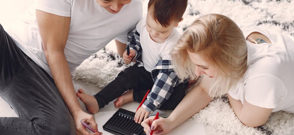 Parents and child enjoying drawing together on the floor, creating memories.