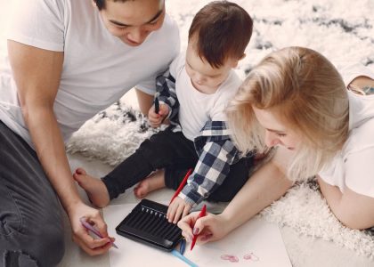 Parents and child enjoying drawing together on the floor, creating memories.