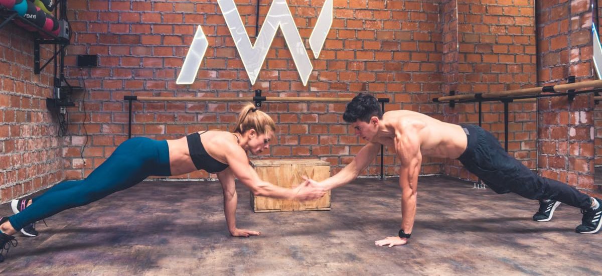 Fit couple working out together in a modern gym, showcasing teamwork and a healthy lifestyle.